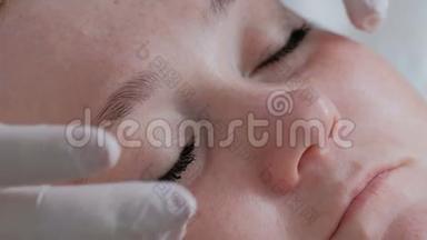 一位戴着白手套的专业美容师的双手在一位美女的眼睛周围涂抹眼霜